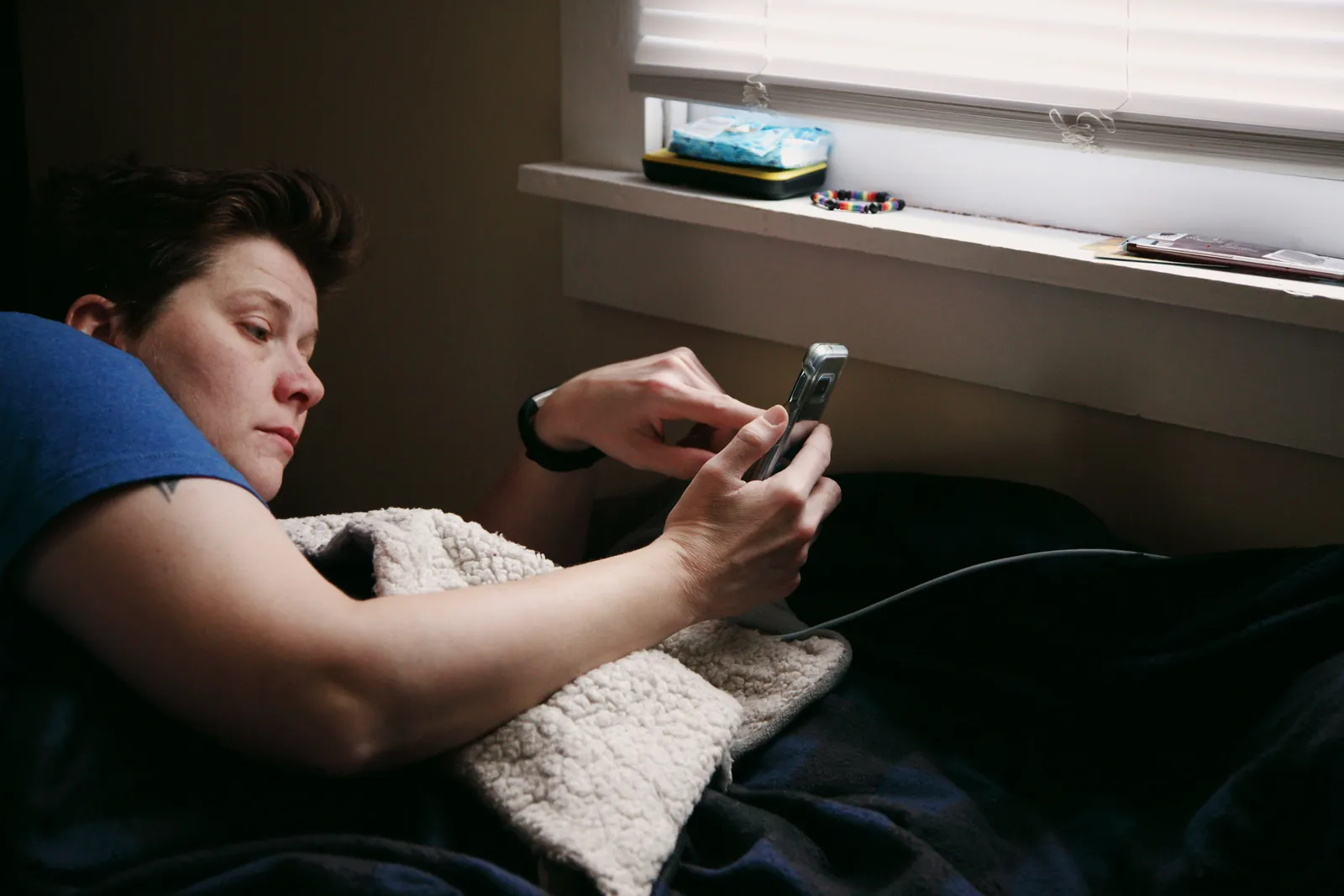 Hombre en la cama de noche mirando el móvil, buscando síntomas en internet por ansiedad por la salud