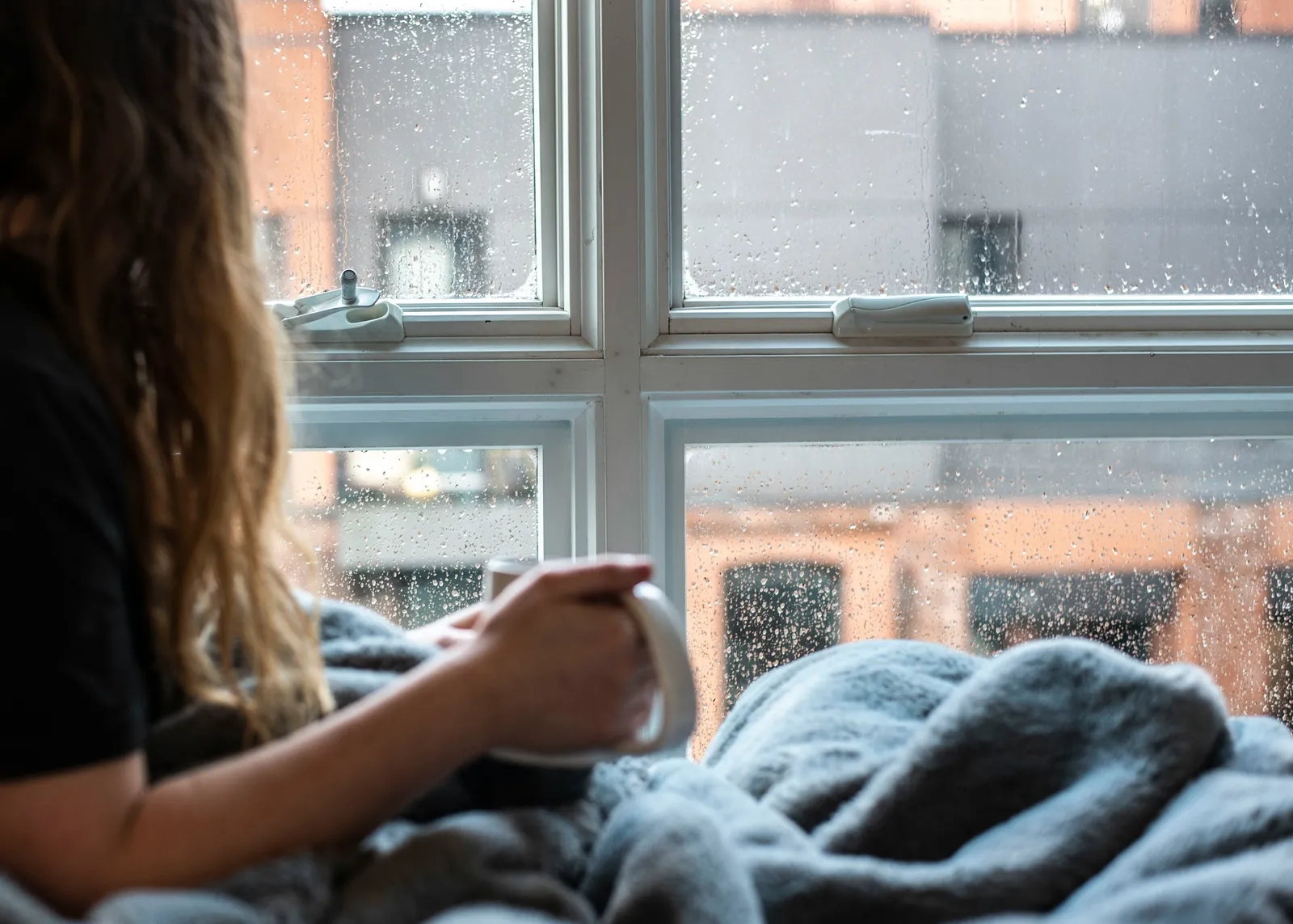 Persona mirando por una ventana con lluvia, imagen sobre la dificultad para identificar y describir las emociones